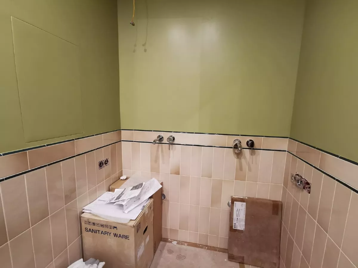 Ремонт ванной комнаты: комбинированная отделка — нижняя часть выложена узкой дизайнерской плиткой бежевого цвета с декоративным бордюром, верхняя часть окрашена в оливковый цвет, установка розеток и сантехнических рамок