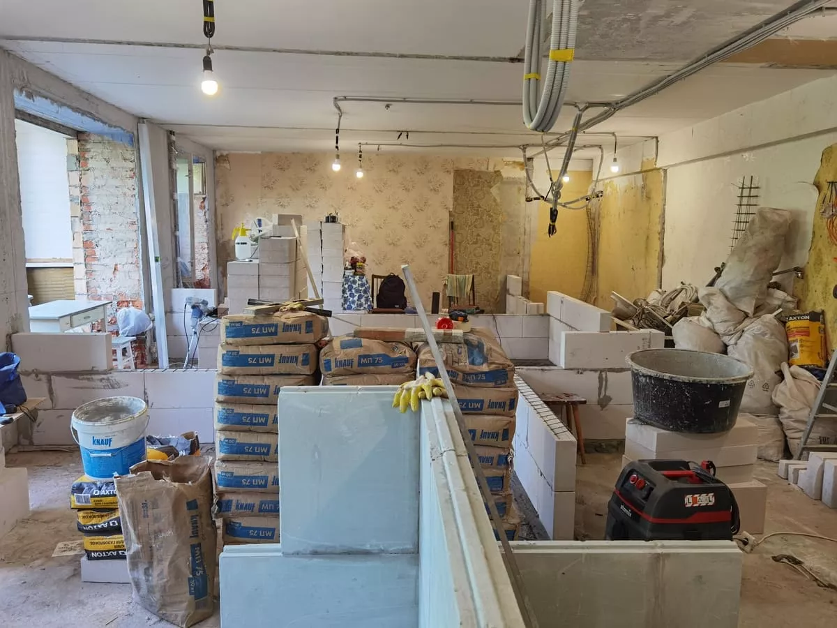 Процесс возведения перегородок из газобетонных блоков: общий вид квартиры, идет кладка стен, видны материалы и лазерный уровень